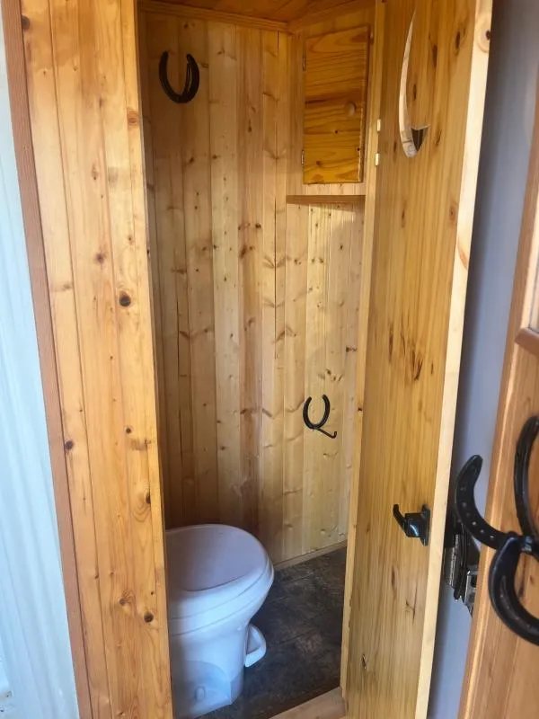 2004 Sundowner 3 Horse Trailer – Weekender Living Quarters – Small bathroom area with a white toilet and natural wood walls and door