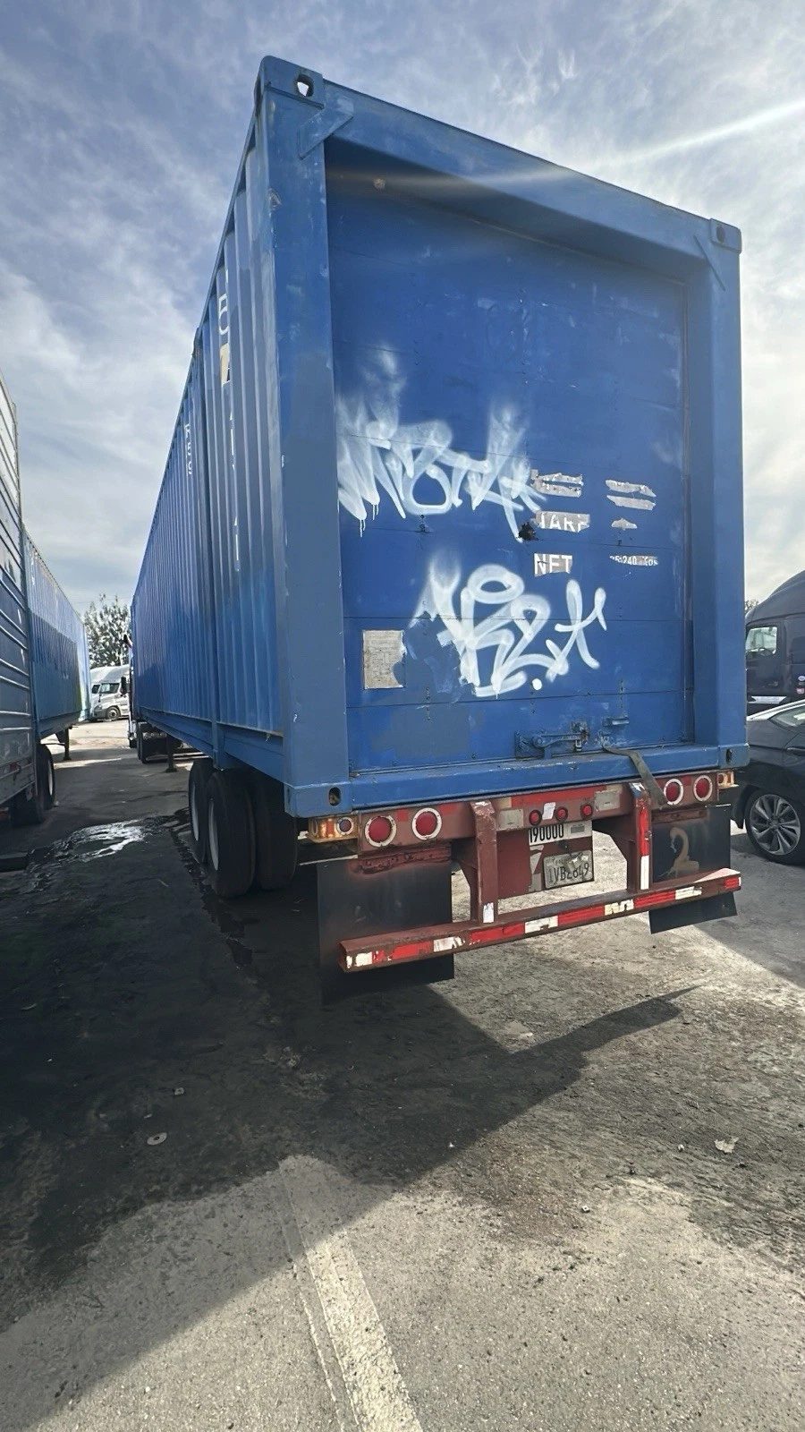 53ft High Cube Shipping Container – Used, Cargo Worthy – blue container on trailer with graffiti on end wall