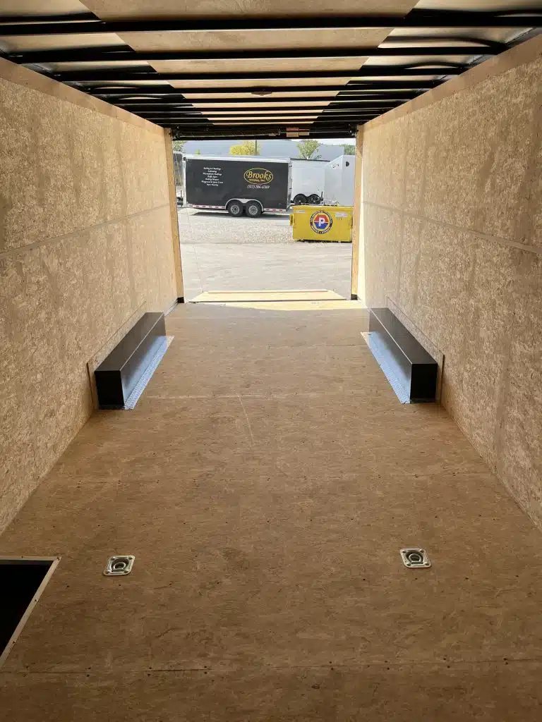 2026 Millennium 24 ft Car Hauler – Silver Hero – Interior view looking out through the open rear ramp door toward a parking lot