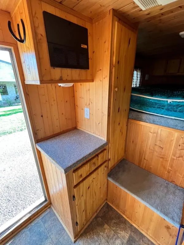 2004 Sundowner 3 Horse Trailer – Weekender Living Quarters – Wood-paneled interior showing a countertop, storage cabinets, and stairs to the sleeping area
