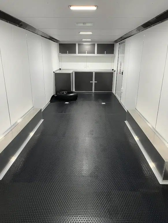 2026 Millennium 28 ft Aluminum Car Hauler – Extreme – A full interior view of the trailer showing white walls, black flooring, and front cabinets