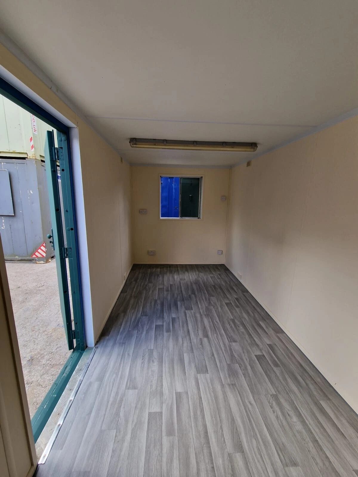 20ft Anti-Vandal Office Canteen – Insulated Steel Workspace – empty office interior with cream walls and grey wood-effect flooring