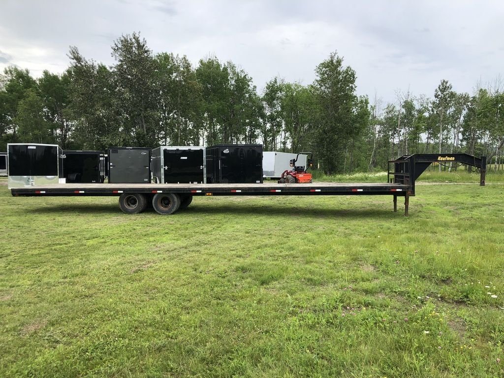 2002 Kaufman 40 ft Equipment Trailer – Toolbox – Full side view of a black gooseneck flatbed trailer on green grass