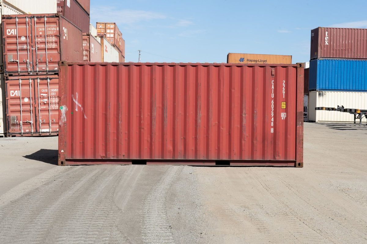 20ft Used Shipping Container – Cargo-Worthy, Standard Height – side view of weathered red shipping container in yard
