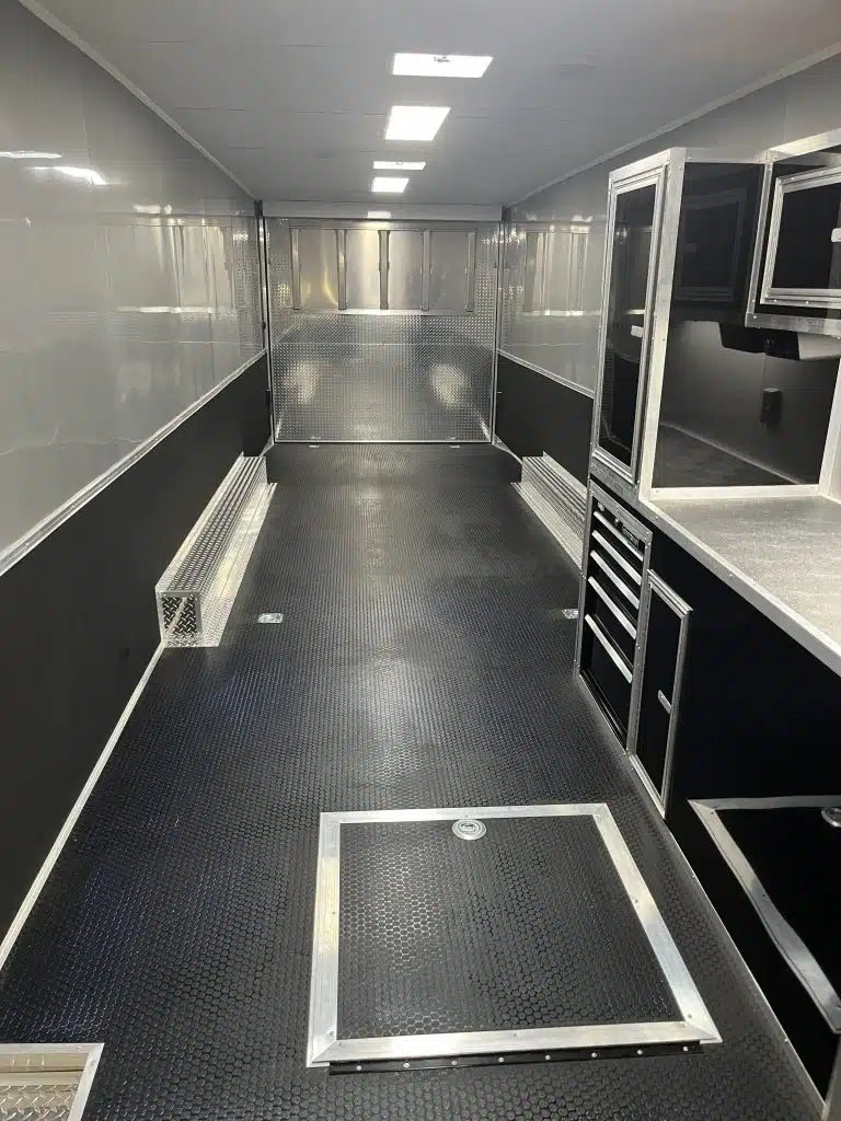 2025 Millennium 34 ft Car Trailer – Corner Bathroom – Empty interior cargo area with black rubber flooring and built-in metal storage cabinets
