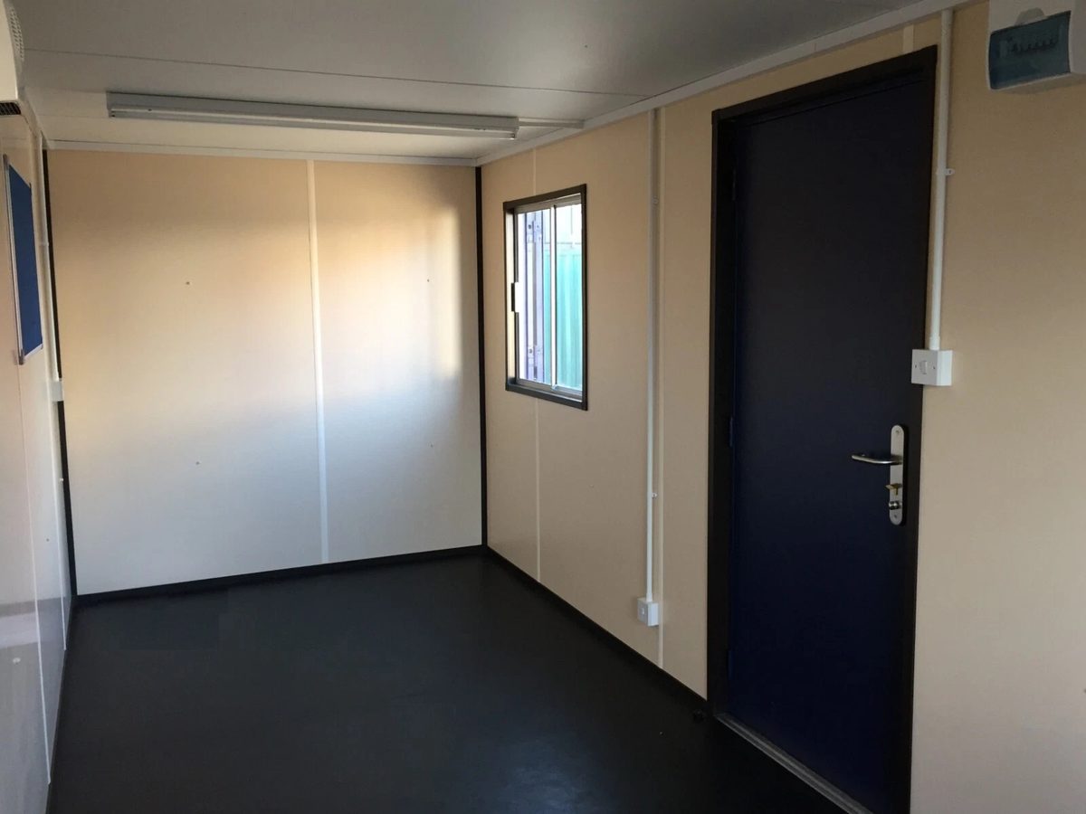 20ft Portable Office Cabin – Insulated Steel Workspace – empty office interior with cream walls and dark entry door