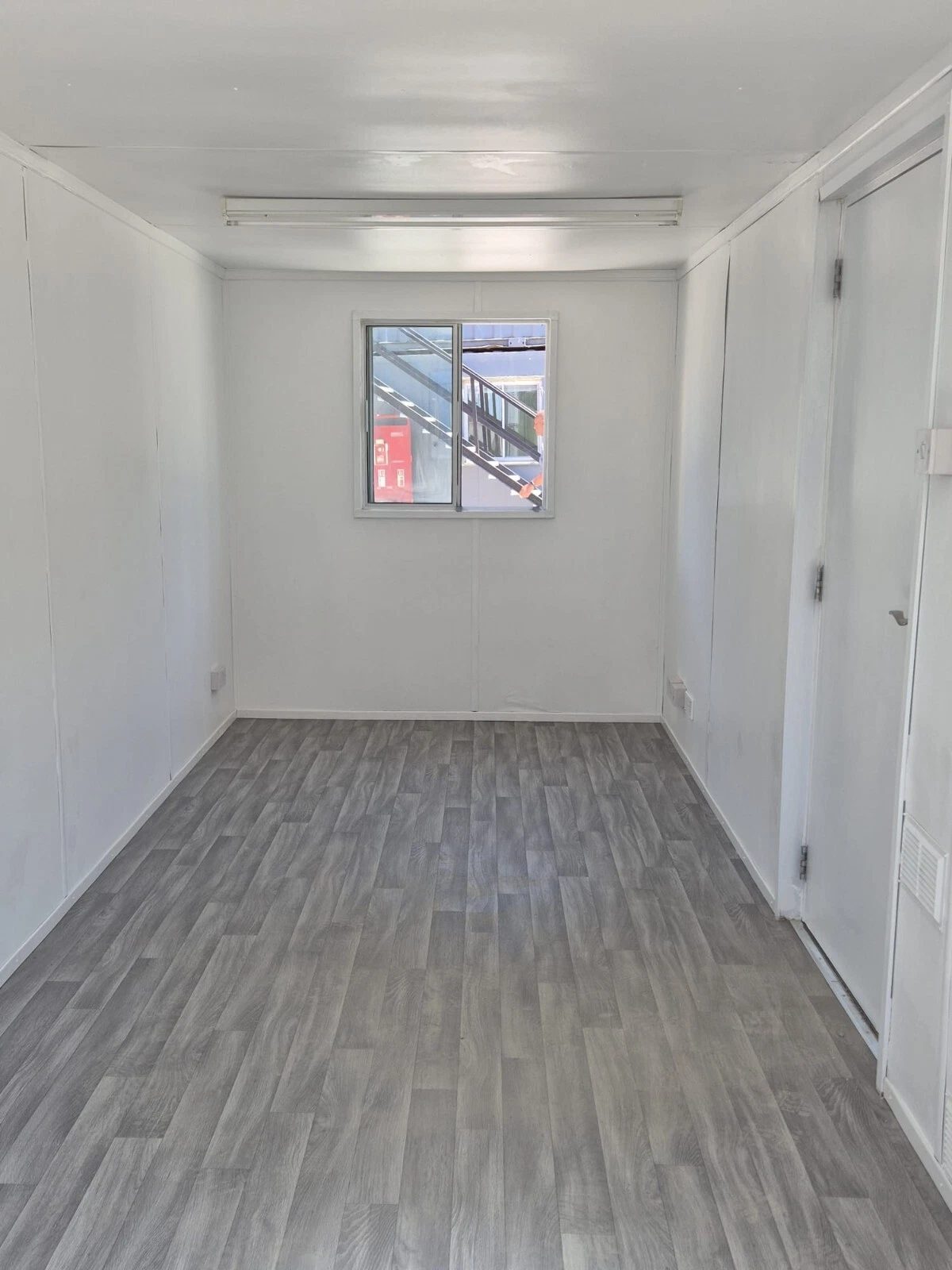 20ft Mobile Office Container – Green, Open Plan – Empty office interior with white walls and grey wood-effect flooring