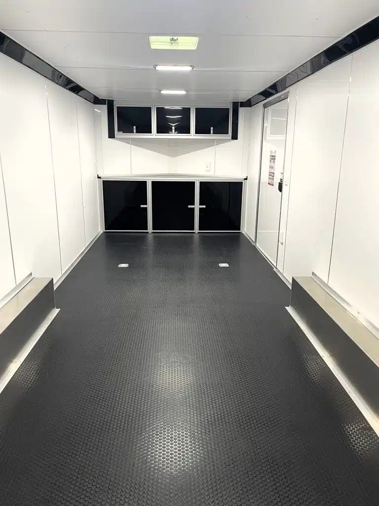 2026 Millennium 24 ft Blaze Car Hauler – Black Aluminum – Interior view facing forward showing white walls, black cabinets, and textured floor
