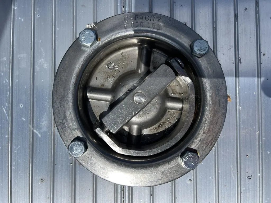 2024 Cargo Pro 12 ft Dump Trailer – Aluminum – A circular metal recessed tie-down ring installed in the aluminum trailer bed