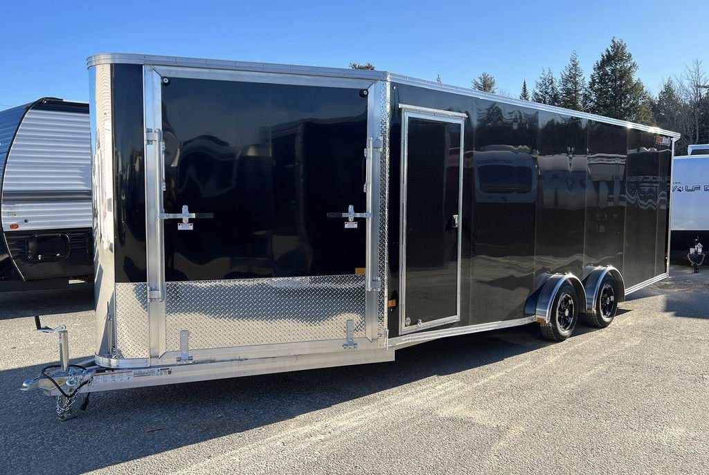 2024 Sno Pro 22 ft Snowmobile Trailer – Extra Height – A three-quarter exterior view of a black enclosed trailer showing the side door and hitch