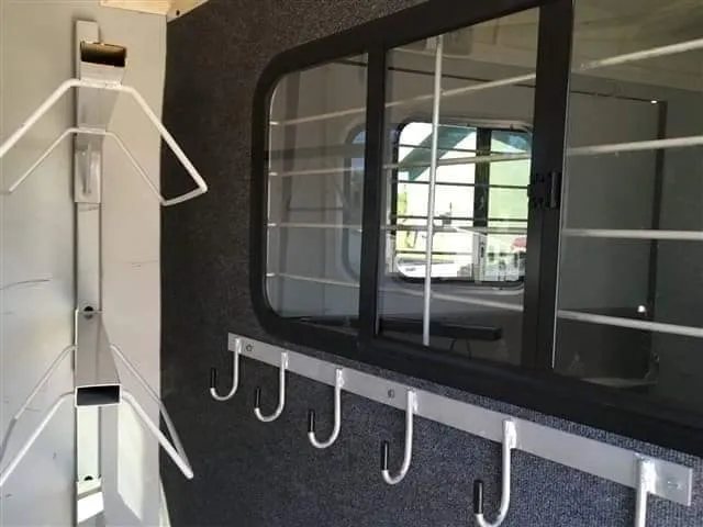 2007 Hawk 2 Horse Bumper Pull Trailer – Side Ramp – Inside the tack room area showing saddle racks and bridle hooks on a carpeted wall