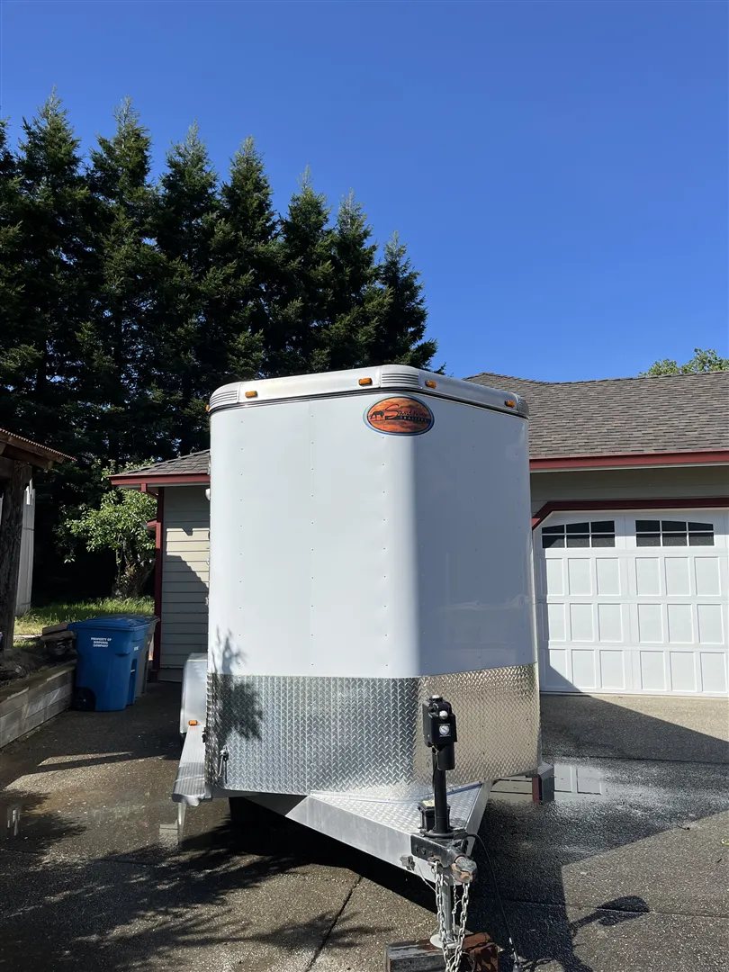 2013 Sundowner Sportsman 3 Horse Trailer – Extra-Large Tack Room – A straight front view of the white horse trailer showing the hitch and diamond plate