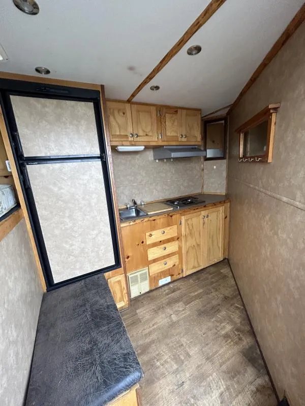 2002 Silverado 3 Horse Gooseneck Trailer – Wood Interior – Wide shot of the small kitchen and living area with wood-look flooring