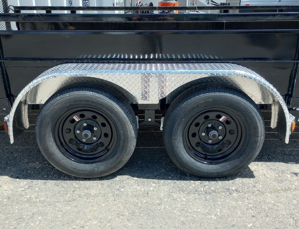 2024 PJ Trailers 14 ft Utility – Solid Metal Sides – Close-up of the dual axles with black rims and silver diamond plate fenders
