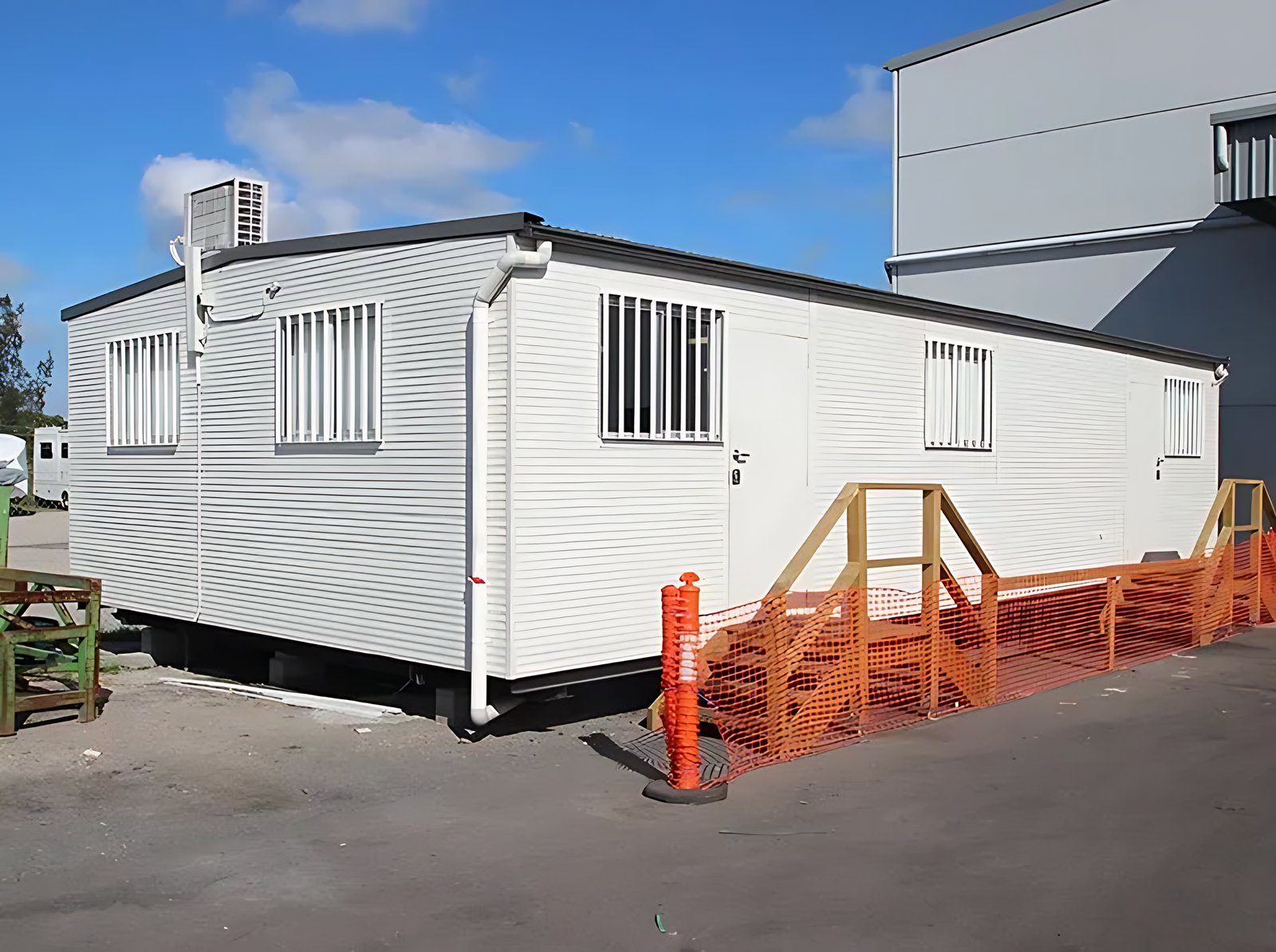 Custom Portable Steel Building – Office, Workshop or Storage – white portable building with barred windows and wooden entry steps