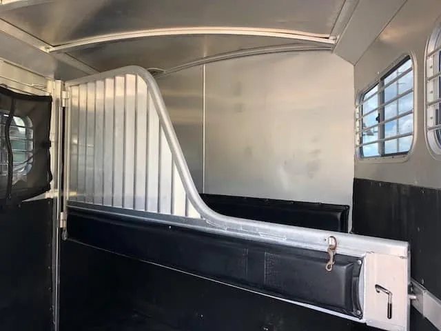 2004 4 Star 2 Horse Gooseneck Trailer – Slant Load, White – Interior view showing the aluminum stall divider and side windows with bars