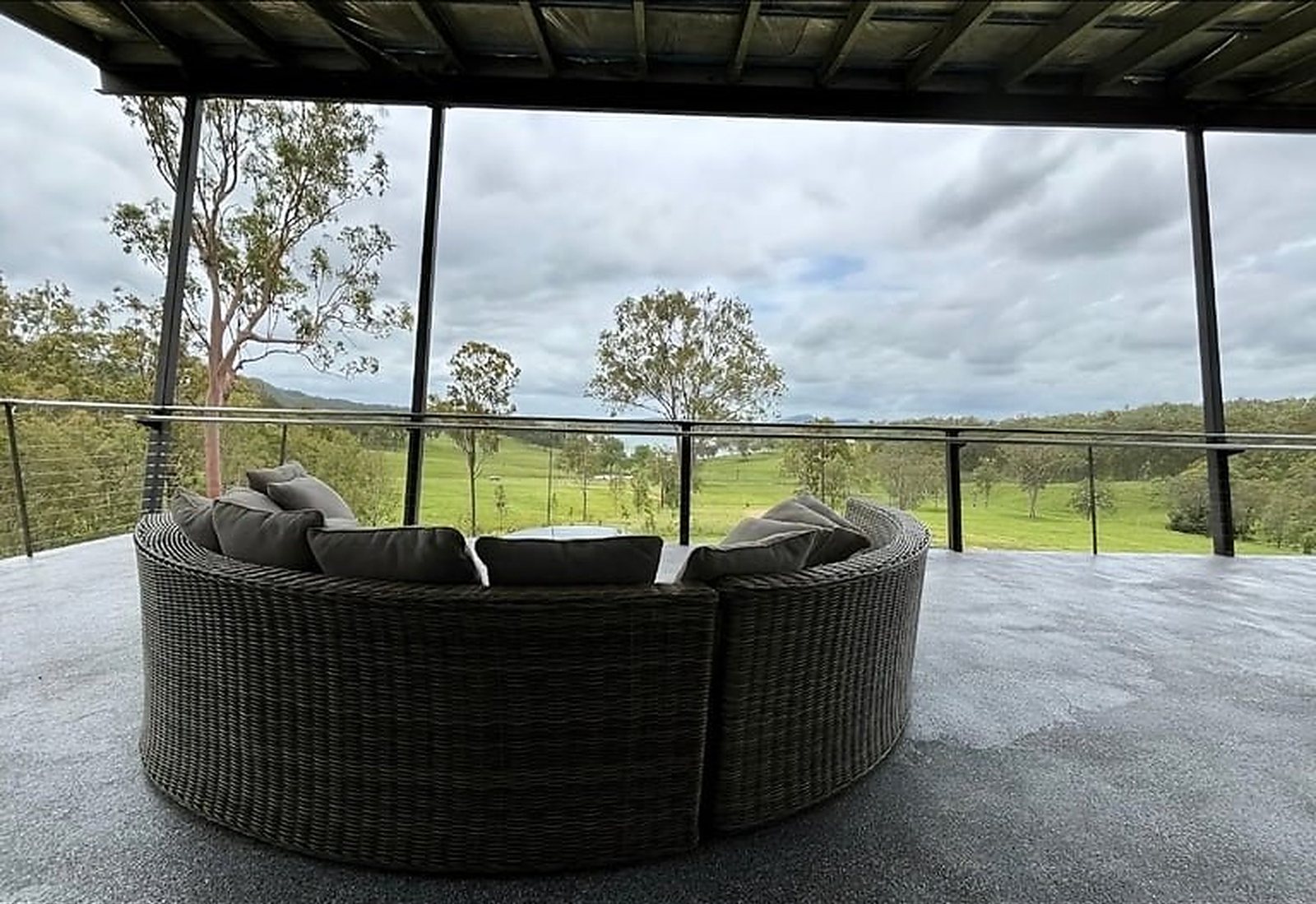 3-Bedroom Two-Story Container Home – Upper Terrace & Patio – The 600 sq ft covered upper terrace is built for entertaining, with a curved sectional and glass balustrade — furniture and appliances shown for illustration only; not included