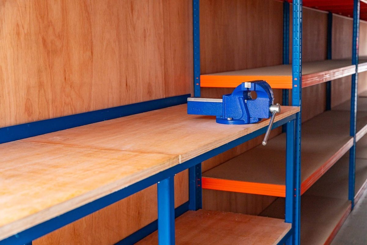 40ft Tunnel Container Workshop – Dual-End Access and Shelving – wooden workshop bench with blue vise and storage shelving