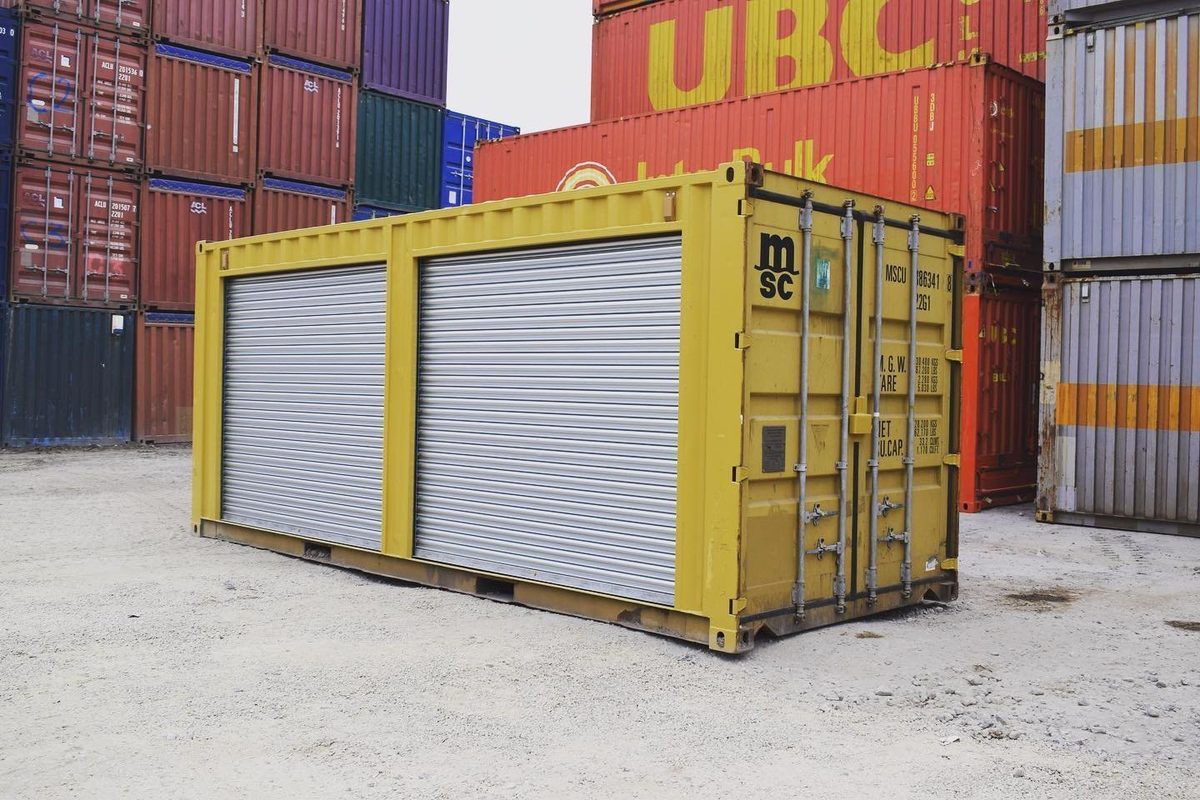 20ft Used Storage Container – Dual Side Roll-Up Doors – Yellow storage container with two closed silver side shutters and closed end doors