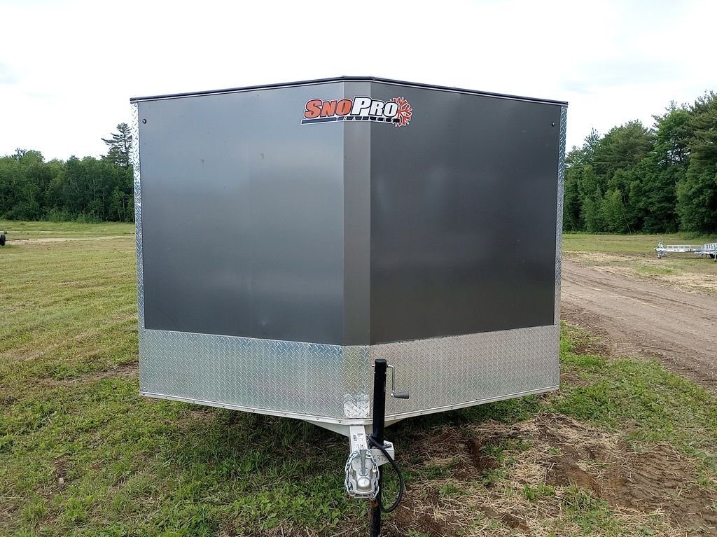 2022 Sno Pro Trailers Hybrid 2.0 – Charcoal Snowmobile Trailer – A direct front view of the V-nose charcoal grey trailer in a field