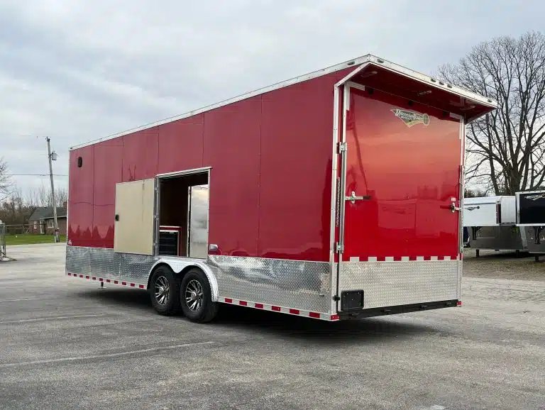 2026 Millennium 24 ft Car Hauler – Red, Econo-Max – Rear three-quarter view of a red enclosed trailer with rear wing and open side door