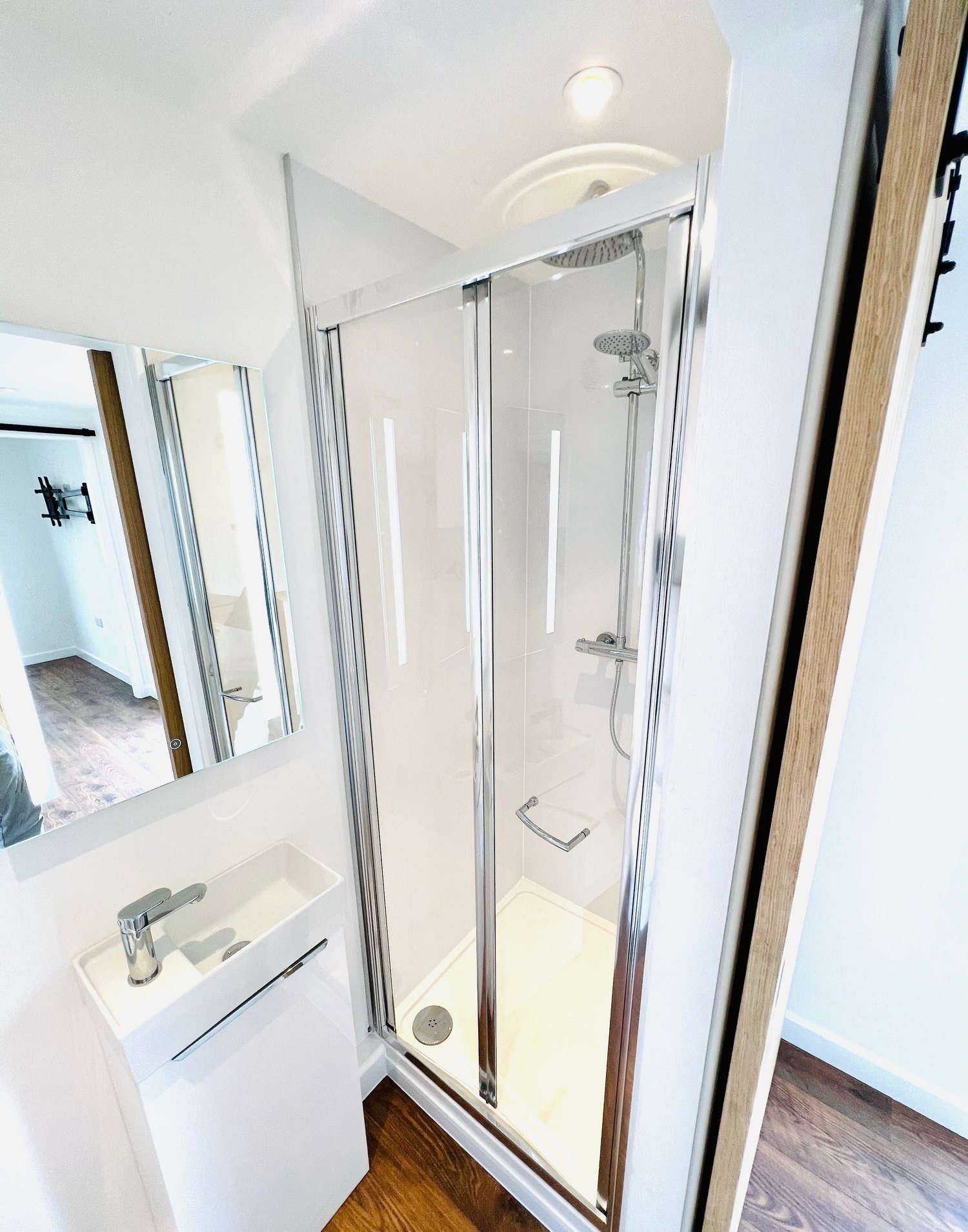 20ft Container Home – One Bed Box, 1 Bedroom – Efficiency meets style in this refurbished shipping container bathroom with a glass shower enclosure and sleek vanity