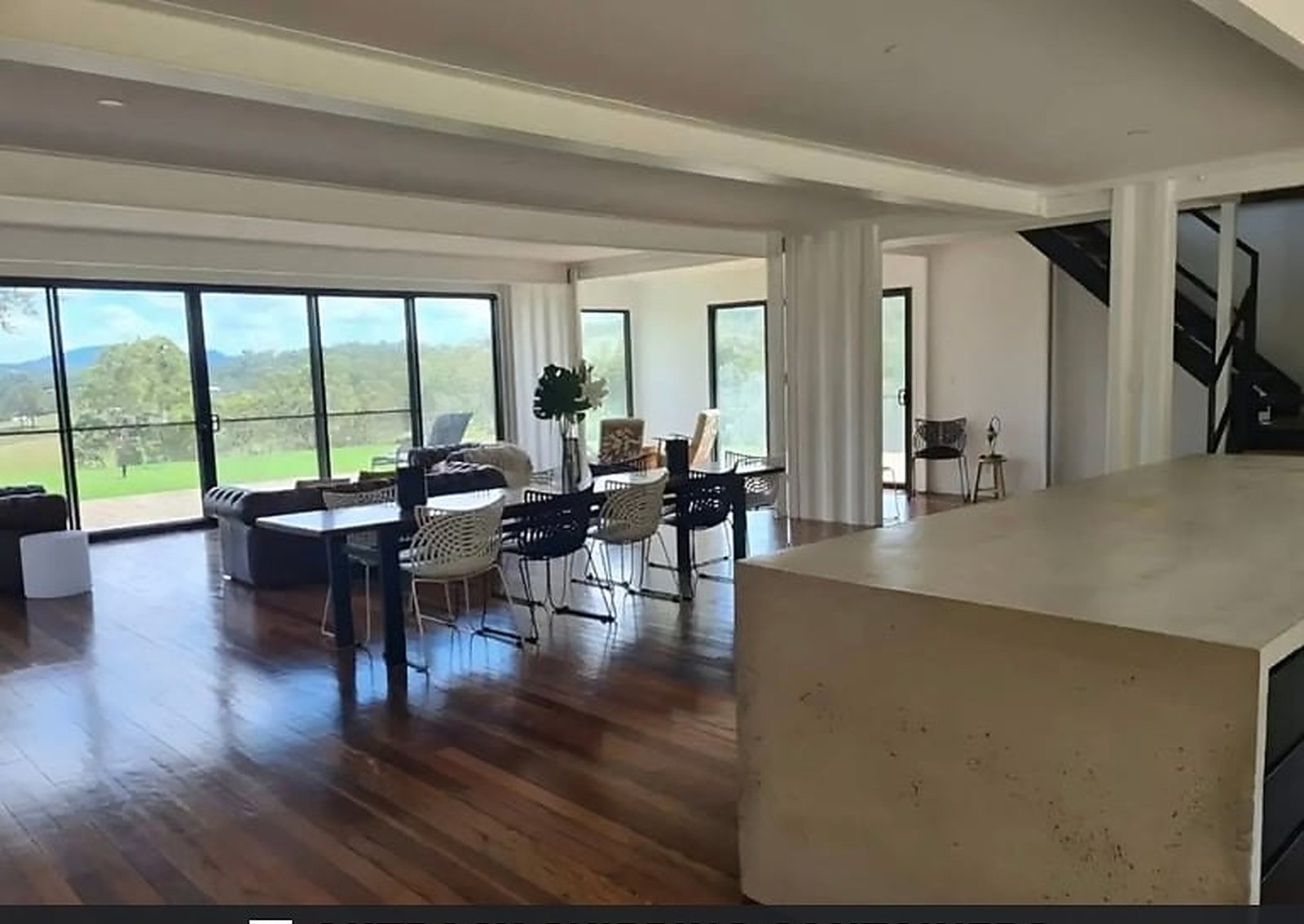 3-Bedroom Two-Story Container Home – Upper Terrace & Patio – Open-plan kitchen with concrete-look island, breakfast seating and direct flow to the dining table — furniture and appliances shown for illustration only; not included