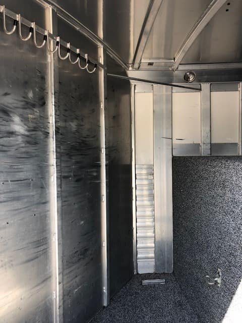 2004 4 Star 2 Horse Gooseneck Trailer – Slant Load, White – Dressing room area with bridle hooks mounted on the wall and dark flooring