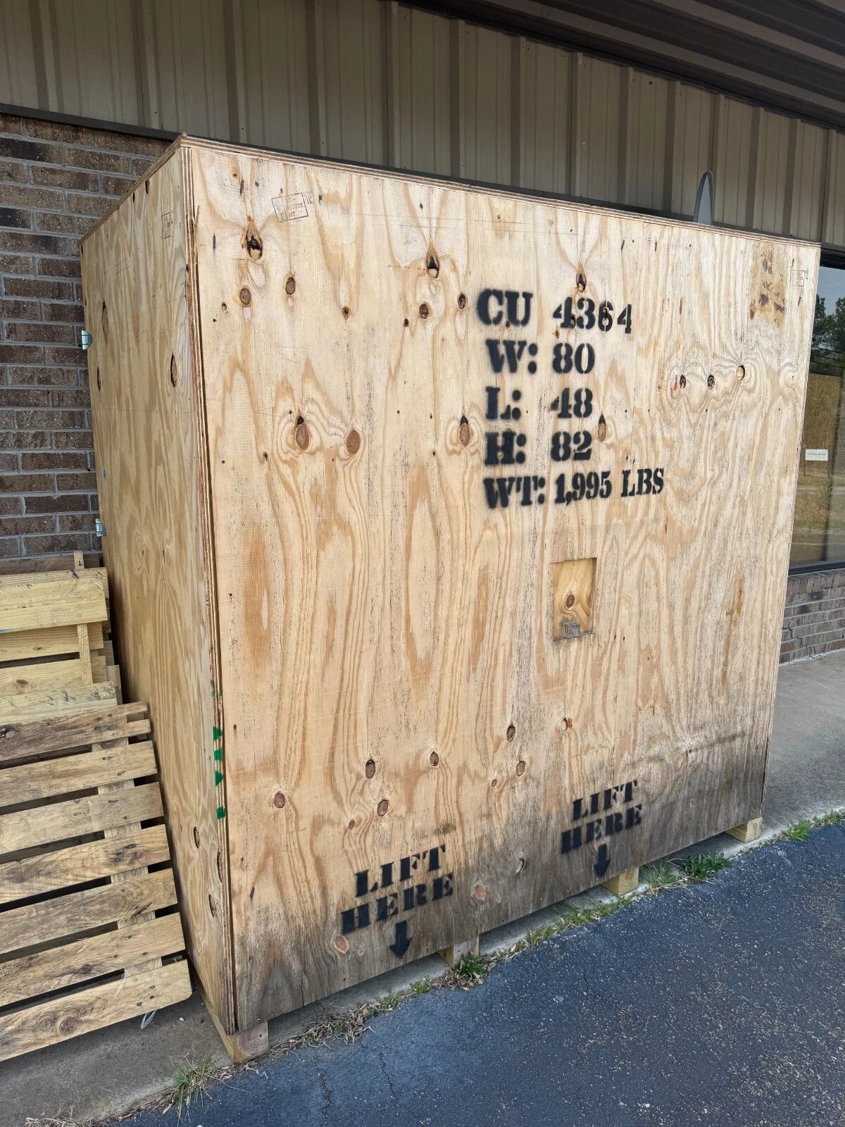 80in Used Wooden Shipping Crate – Reinforced Corners – three-quarter exterior view of wooden shipping crate beside pallets