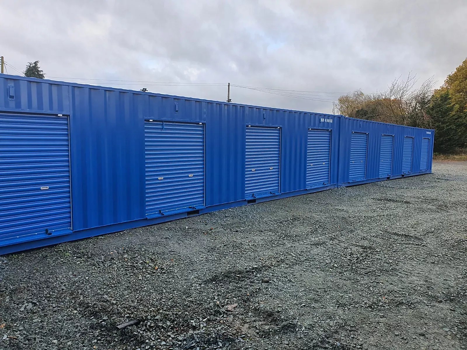 40ft High Cube Storage Container – Insulated, Plywood-Lined – Row of blue storage containers with closed roller shutter doors