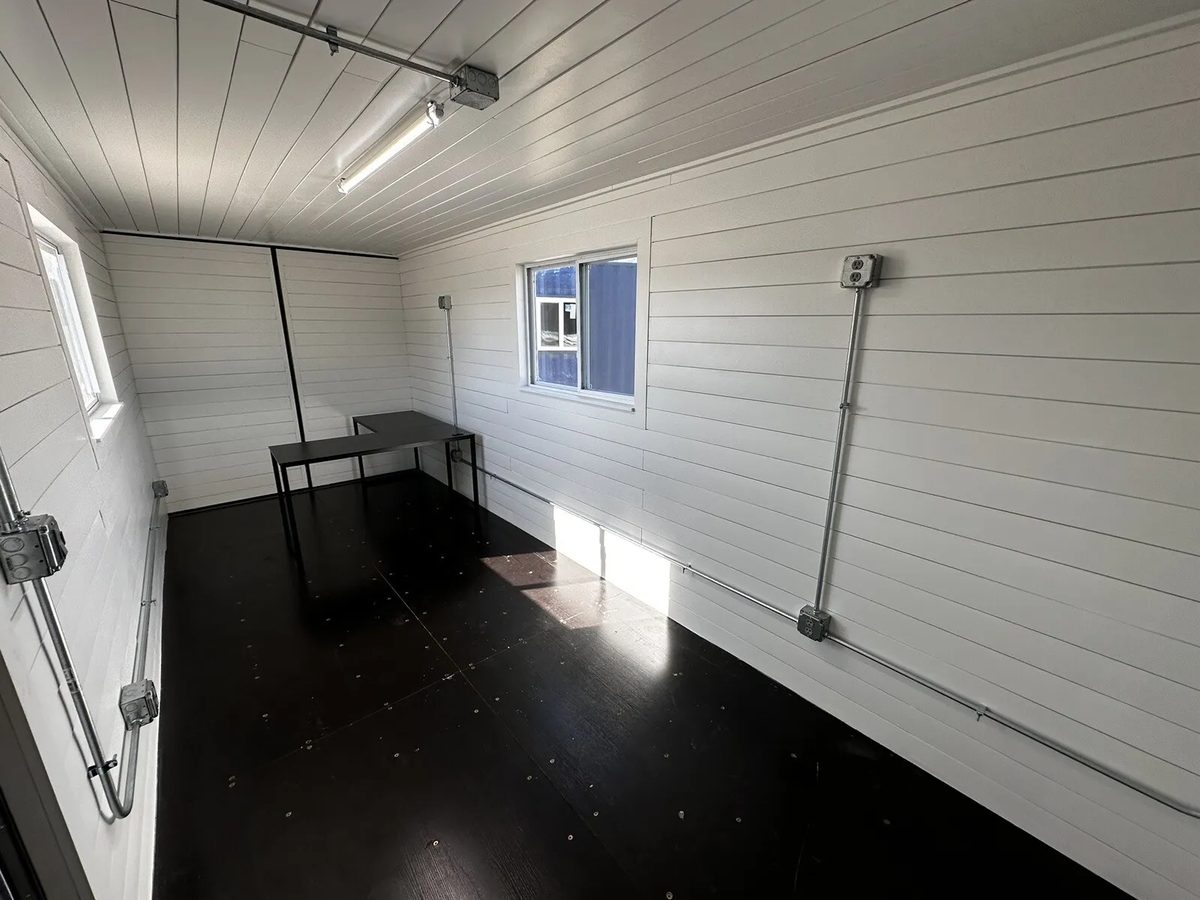 20ft Prefabricated Metal Office – Slate Gray Shiplap – White shiplap interior with black desk and exposed electrical conduit
