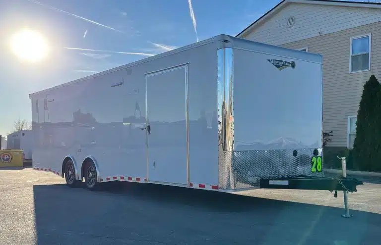 2026 Millennium 28 ft Car Hauler – White – Three-quarter front view of a white car hauler trailer against a bright sky
