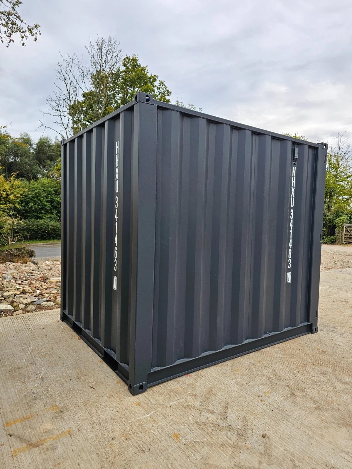 8ft New Shipping Container – Lockbox and Barred Windows – three-quarter exterior view of grey container without doors visible