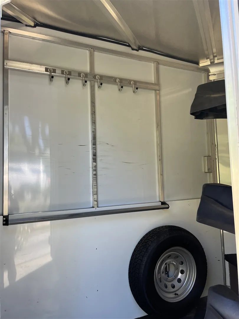 2013 Sundowner Sportsman 3 Horse Trailer – Extra-Large Tack Room – Inside the tack room showing bridle hooks and a spare tire mounted on the wall