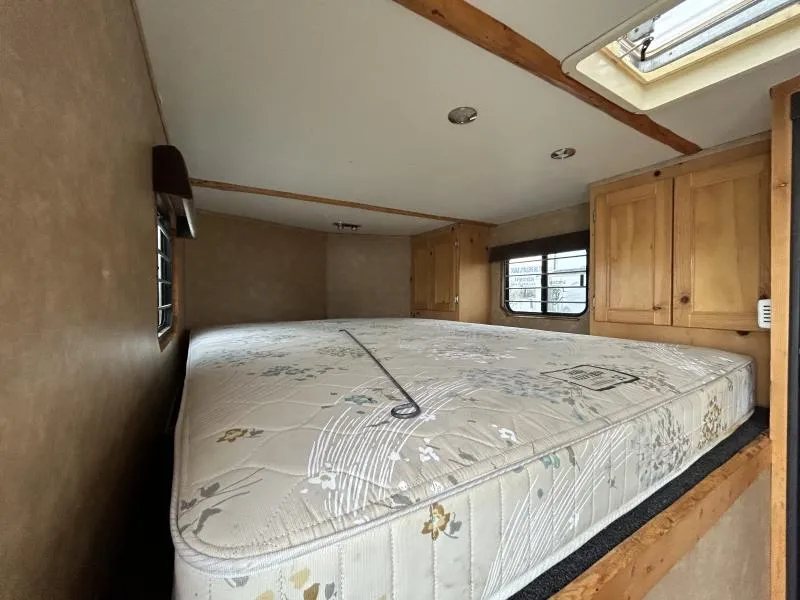 2002 Silverado 3 Horse Gooseneck Trailer – Wood Interior – Living quarters sleeping area featuring a mattress and wooden storage cabinets