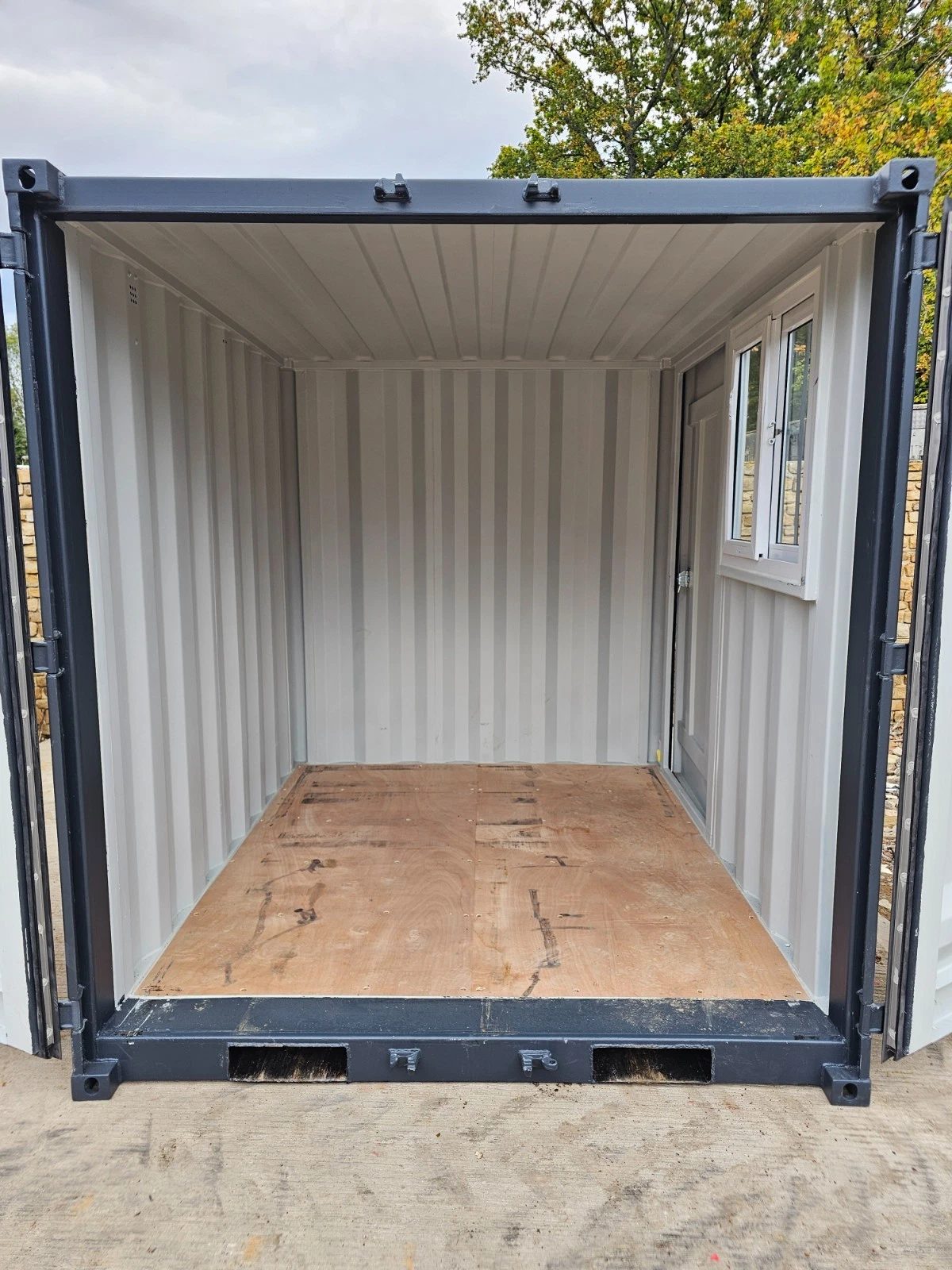 8ft New Shipping Container – Lockbox and Barred Windows – empty container interior with plywood floor and side window (16)