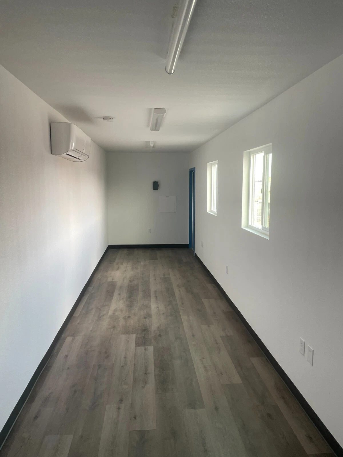 40ft Converted Container Office – Accessible Restroom – Empty office interior with wood-look flooring and wall-mounted air conditioner