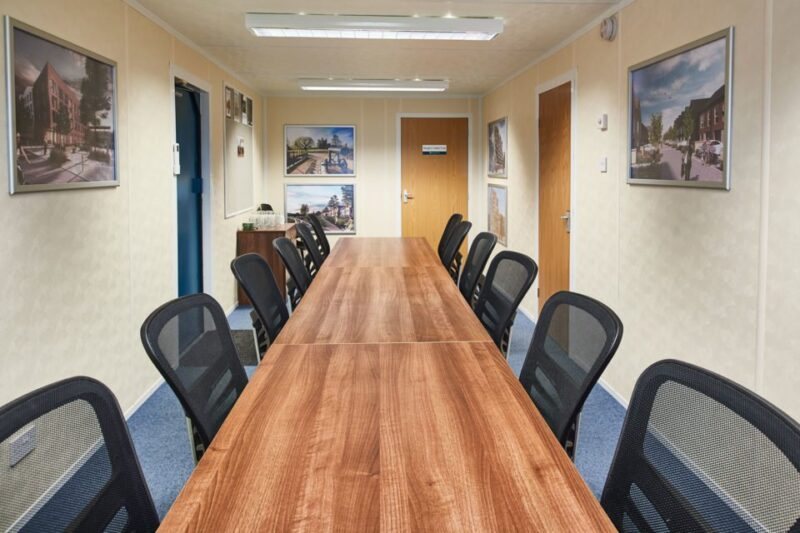 32 ft ECOlink Meeting Room Cabin – Blue – Perspective view down a long conference table inside a portable cabin with office seating