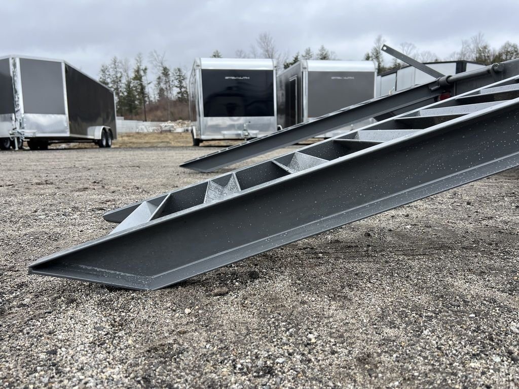 2024 Diamond C Deckover Equipment Trailer – Cement Gray – Side angle close-up of the gray metal flip-knee loading ramps extended down