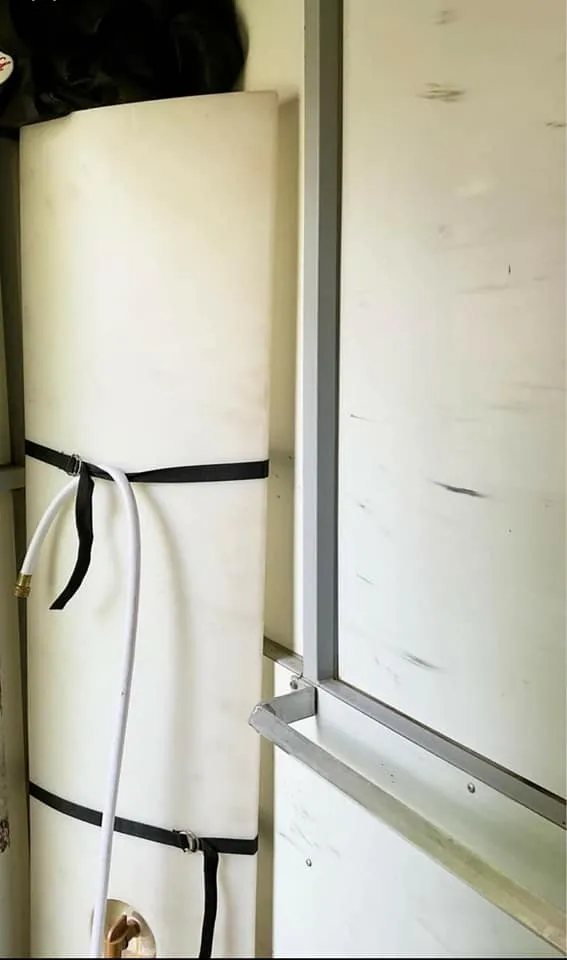 1999 Sundowner 3 Horse Trailer – Removable Rear Tack – White vertical water storage tank secured with black straps inside a trailer