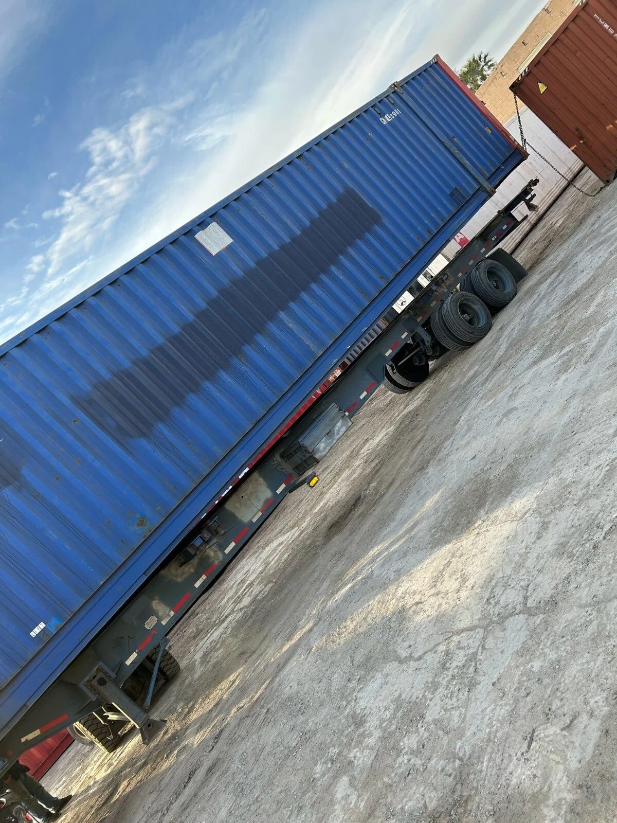 53ft High Cube Steel Shipping Container – Double End Doors – tilted side view of blue shipping container on trailer