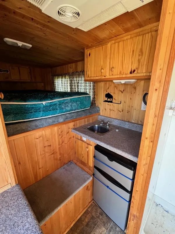 2004 Sundowner 3 Horse Trailer – Weekender Living Quarters – Compact kitchenette with sink, microwave, refrigerator, and sleeping bunk in the background