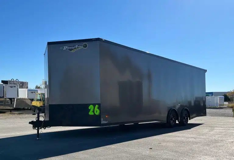 2025 Millennium 26 ft Car Hauler – Charcoal – A three-quarter exterior view of a grey enclosed car hauler trailer with black trim