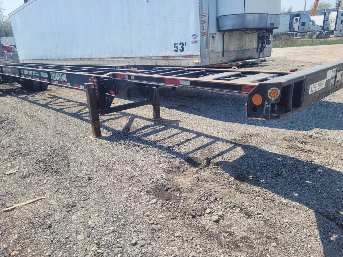 53ft Used Container Chassis – 2011, Spring Suspension – angled exterior view of empty chassis in gravel yard