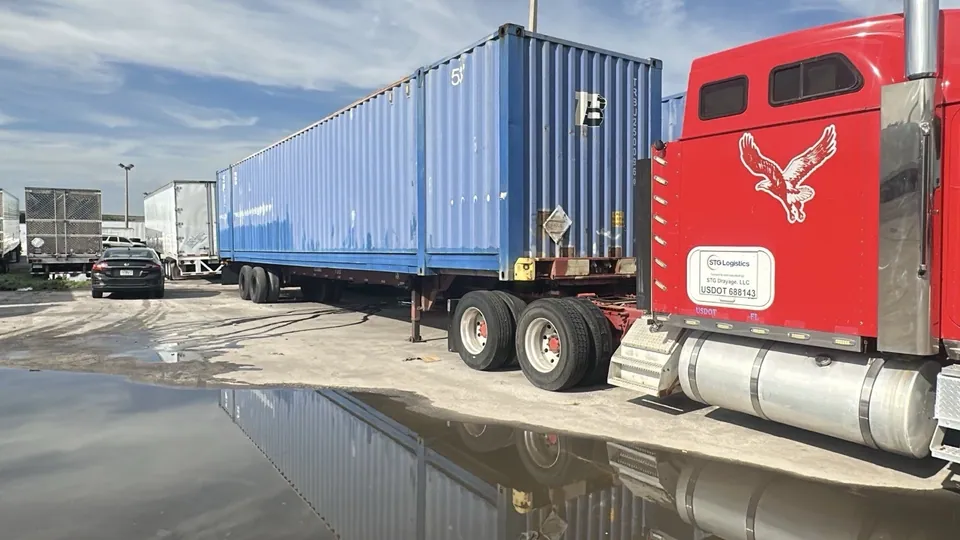 53ft High Cube Shipping Container – Used, Cargo Worthy – blue shipping container on chassis beside red truck