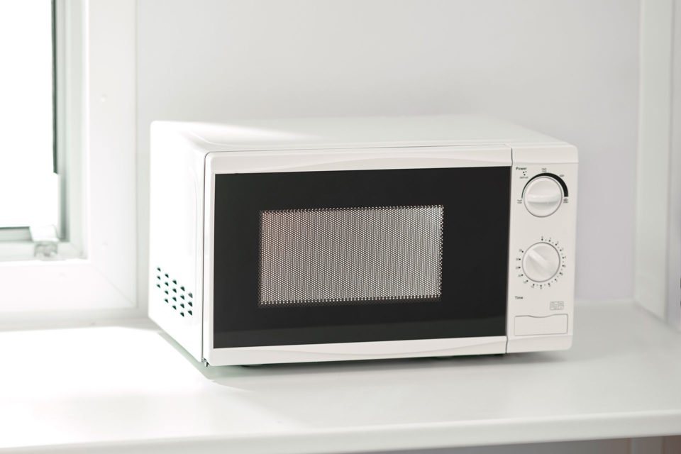 Site Cabin Countertop Microwave – 700-Watt Output – A white countertop microwave sitting on a white surface inside a cabin