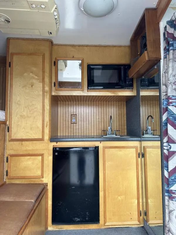 2004 Hart 3 Horse Gooseneck Trailer – Weekender Living Quarters – Living area kitchenette with wood cabinets, microwave, sink and small refrigerator