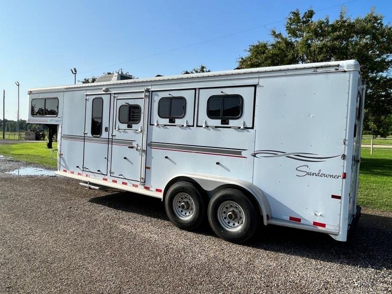2004 Sundowner 3 Horse Trailer – Weekender Living Quarters – Side profile of the horse trailer showing doors and horse stall windows on gravel
