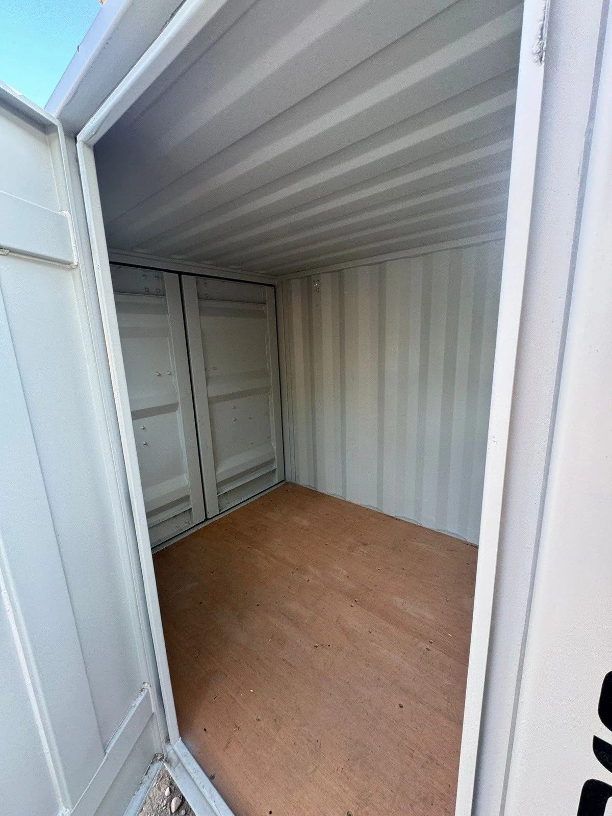 7ft New Storage Container – Window and Personnel Door – empty container interior with plywood floor and open entry door
