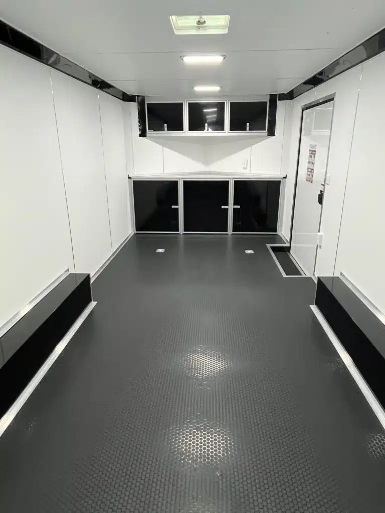 2025 Millennium 20 ft Car Hauler – Black-Out Package – Interior view looking toward the front showing black cabinets and white wall panels